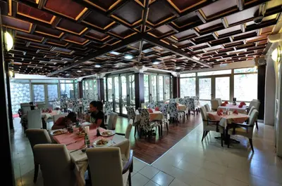 a dining room with tables and chairs and people sitting at them at Vila Đurić - Ex Hotel Đurić in Petrovac na Moru