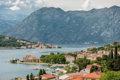 a town on the shore of a lake with mountains at Apartments Magic Sea View in Kotor