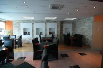 a restaurant with black chairs and tables and a brick wall at Accommodation Dolcino in Ulcinj