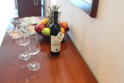 a bottle of wine and a bowl of fruit on a table at Accommodation Dolcino in Ulcinj