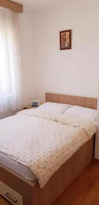 a bed in a bedroom with a picture on the wall at Pjerotic Apartment in Budva