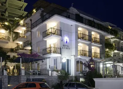 a white building with cars parked in front of it at Hotel Azimut in Sveti Stefan