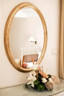 a mirror on top of a table with flowers at Hotel Azimut in Sveti Stefan