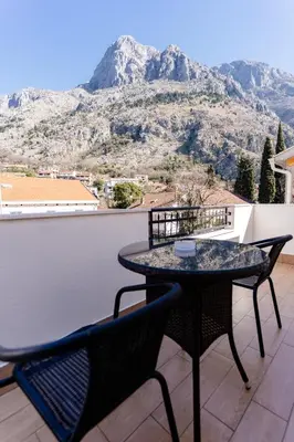 a table and chairs on a balcony with a mountain at Bofima Apartments in Kotor