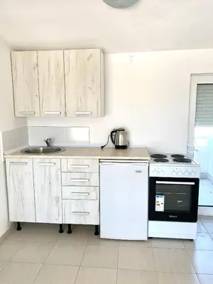 a kitchen with white cabinets and a stove and a sink at Etna Apartments in Ulcinj