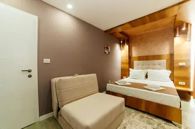 a small bedroom with a bed and a chair at Etna Apartments in Ulcinj