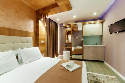 a bedroom with a large white bed and a kitchen at Etna Apartments in Ulcinj