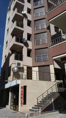 a tall apartment building with a sign in front of it at M&M Apartman 2 in Rafailovici