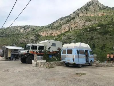 a camper and a truck parked next to a trailer at Hostel Izvor in Podgorica
