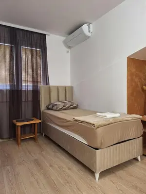 a small bedroom with a bed and a table at Hostel Izvor in Podgorica
