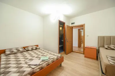 a small bedroom with a bed and a door at Hostel Izvor in Podgorica