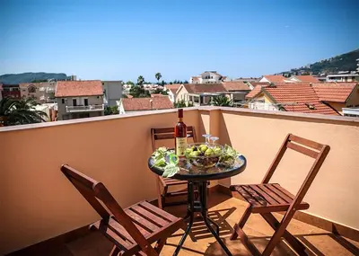 a table with a bottle of wine and two chairs on a balcony at Apartments Stari Ribar in Budva