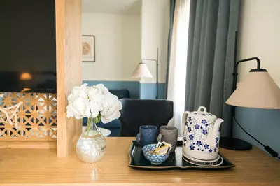 a table with a vase of flowers and cups on it at La Villa Boutique Hotel in Budva