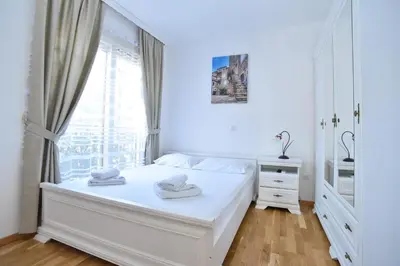 a white bedroom with a bed and a window at Apartment Bojana in Budva