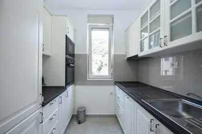 a kitchen with white cabinets and a sink and a window at Apartment Bojana in Budva