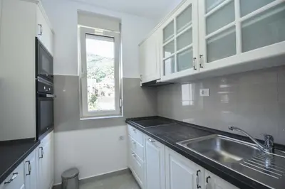 a kitchen with white cabinets and a sink and a window at Apartment Bojana in Budva