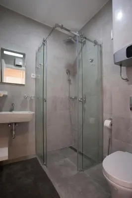 a bathroom with a shower and a toilet and a sink at JK Suites in Budva