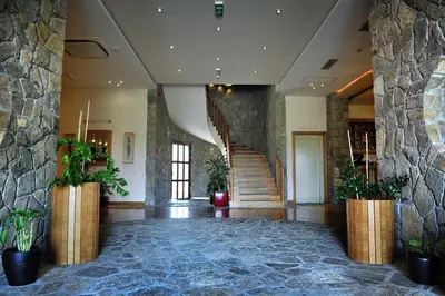 a lobby with a staircase and a stone wall at Hotel Aria in Podgorica