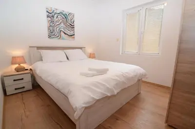 a bedroom with a large bed with white sheets and a window at Maritimo Apartments in Kotor