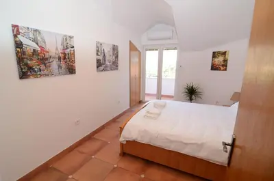 a bedroom with a bed and some pictures on the wall at Maritimo Apartments in Kotor