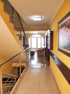 a hallway with yellow walls and a staircase with a couch at Hotel Mimoza in Budva