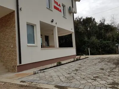 a white building with a sign on the side of it at Apartmani Vila Ebra in Utjeha