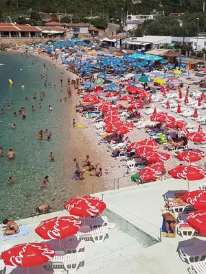a bunch of people on a beach with umbrellas at Apartmani Vila Ebra in Utjeha