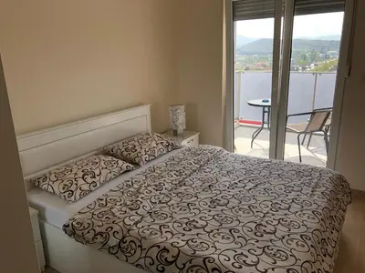 a bedroom with a bed and a view of a balcony at Apartments New City in Podgorica