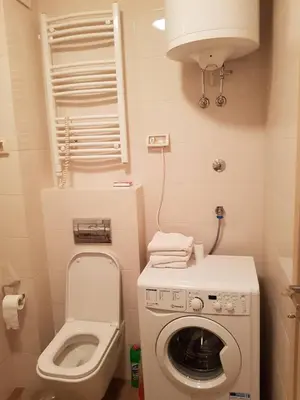 a small bathroom with a washing machine and a toilet at Apartments New City in Podgorica