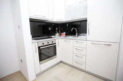a white kitchen with white cabinets and a sink at Sea view Apartments Panorama Przno in Sveti Stefan