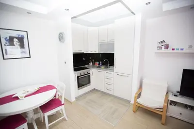 a white kitchen with a table and a dining room at Sea view Apartments Panorama Przno in Sveti Stefan