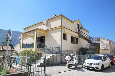 a white car and a scooter parked in front of a house at Loki Apartments in Kotor