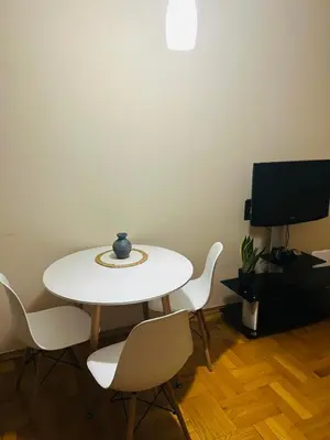 a white table and chairs in a room with a tv at Apartment Flat in Podgorica