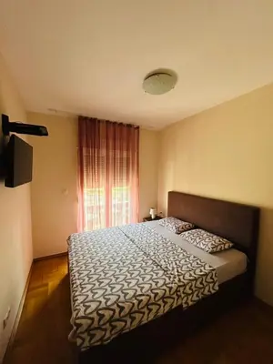 a bedroom with a large bed in front of a window at Apartment Flat in Podgorica