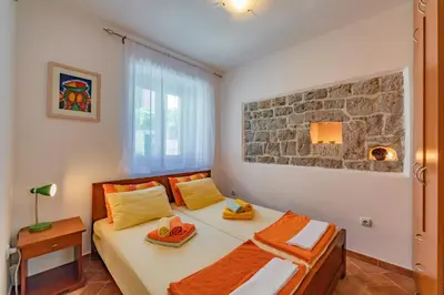 a bedroom with a bed and a stone wall at Apartments Bigovo Veljic in Tivat