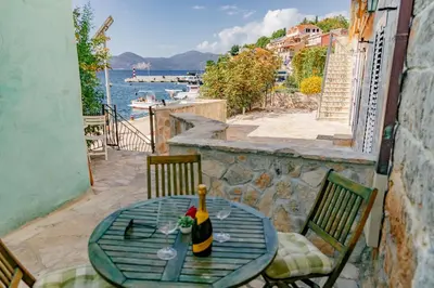 a table with a bottle of wine sitting on a balcony at Apartments Bigovo Veljic in Tivat