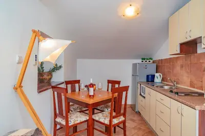 a kitchen with a table and chairs in a kitchen at Apartments Bigovo Veljic in Tivat