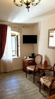 a living room with a tv and a table and chairs at Hotel Monte Cristo in Kotor