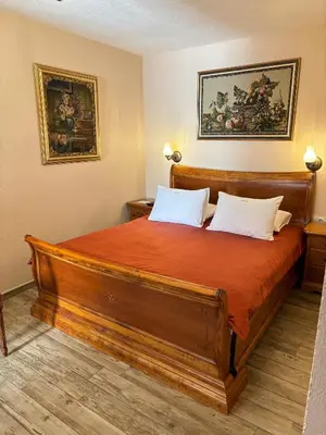 a bedroom with a large wooden bed with red sheets at Hotel Monte Cristo in Kotor