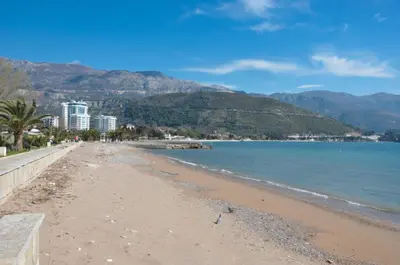 a sandy beach with mountains in the background at Oasis Seaside Rooms in Budva