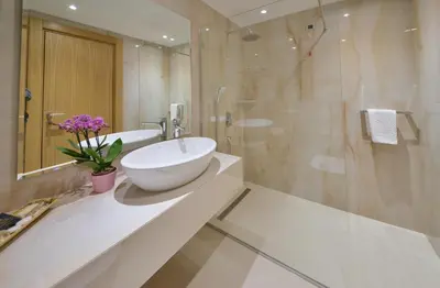 a white bathroom with a sink and a shower at Mediteran Hotel & Resort in Budva