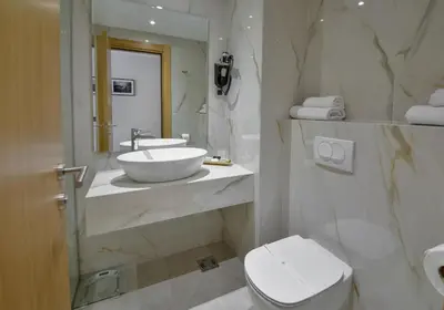 a white bathroom with a sink and a toilet at Mediteran Hotel & Resort in Budva