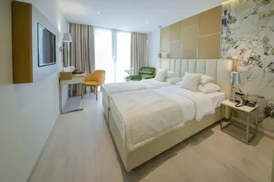 a bedroom with a large bed and a desk at Mediteran Hotel & Resort in Budva