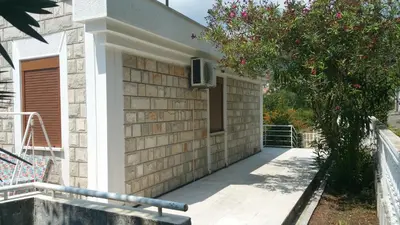 a house with a porch and a tree with pink flowers at Budva City - Villa Antic - Private Pool in Budva