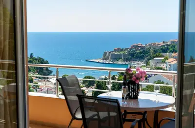 a table with a vase of flowers on a balcony at Apartments Panorama Alaj in Ulcinj