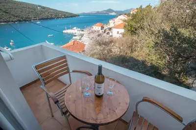 a wooden table with wine glasses on a balcony at Apartments Vesna in Tivat