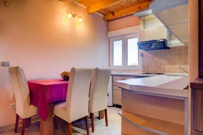 a kitchen with a red table with chairs and a counter at Apartments Vesna in Tivat