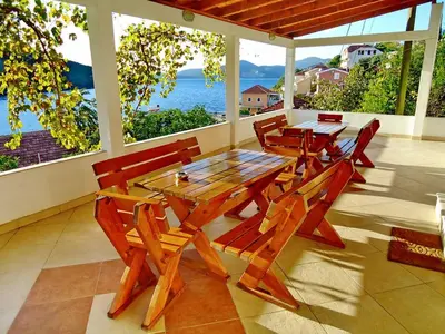 a wooden table and chairs on a patio with the ocean at Apartments Vesna in Tivat
