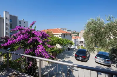 a balcony with purple flowers and cars parked in a parking lot at Apartments Bloom Bečići in Becici