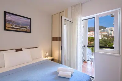 a white bedroom with a bed and a balcony at Apartments Bloom Bečići in Becici